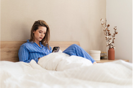 Young woman lying on a bed and, a Person Photo by HalfPoint