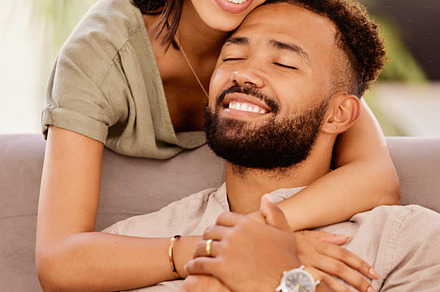 Happy, love and hug with a black couple on the sofa to relax in the living room of the home together. Smile, happy and hugging with a male and female bonding in the lounge of their house for romance, a Photo by Peopleimages.com