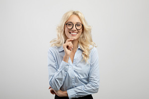 Female business career. Positive young businesswoman touching chin and smiling, a Photo by Prostock-Studio