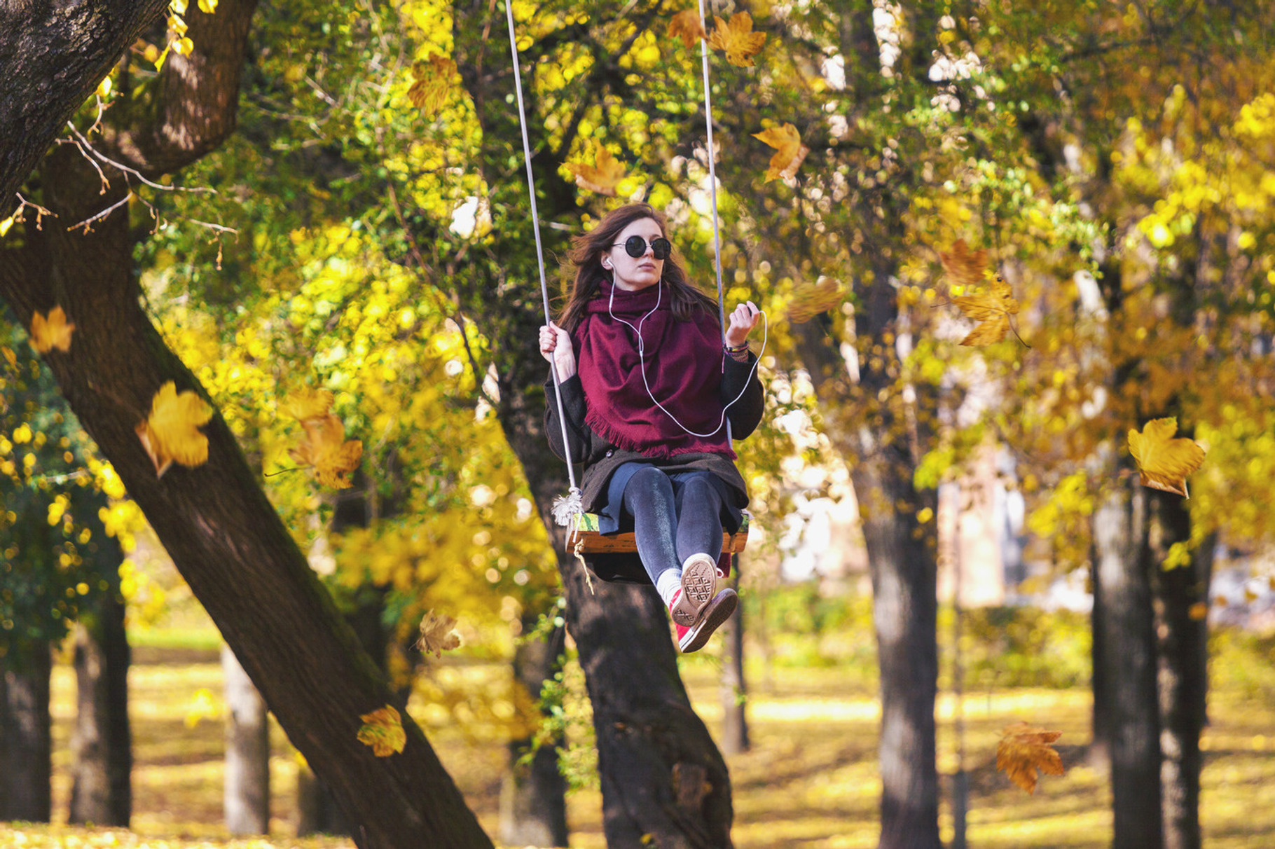 Teenage girl swinging in autumn park, a Person Photo by BOOCYS