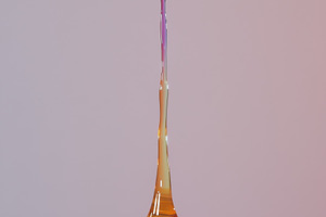 A close-up of a colorful liquid droplet forming a tall, slender column above a, a Photo by Textures & Backgrounds