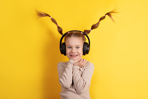 Smiling young girl in headphones with playful pigtails against v, a Person Photo by Ales Munt