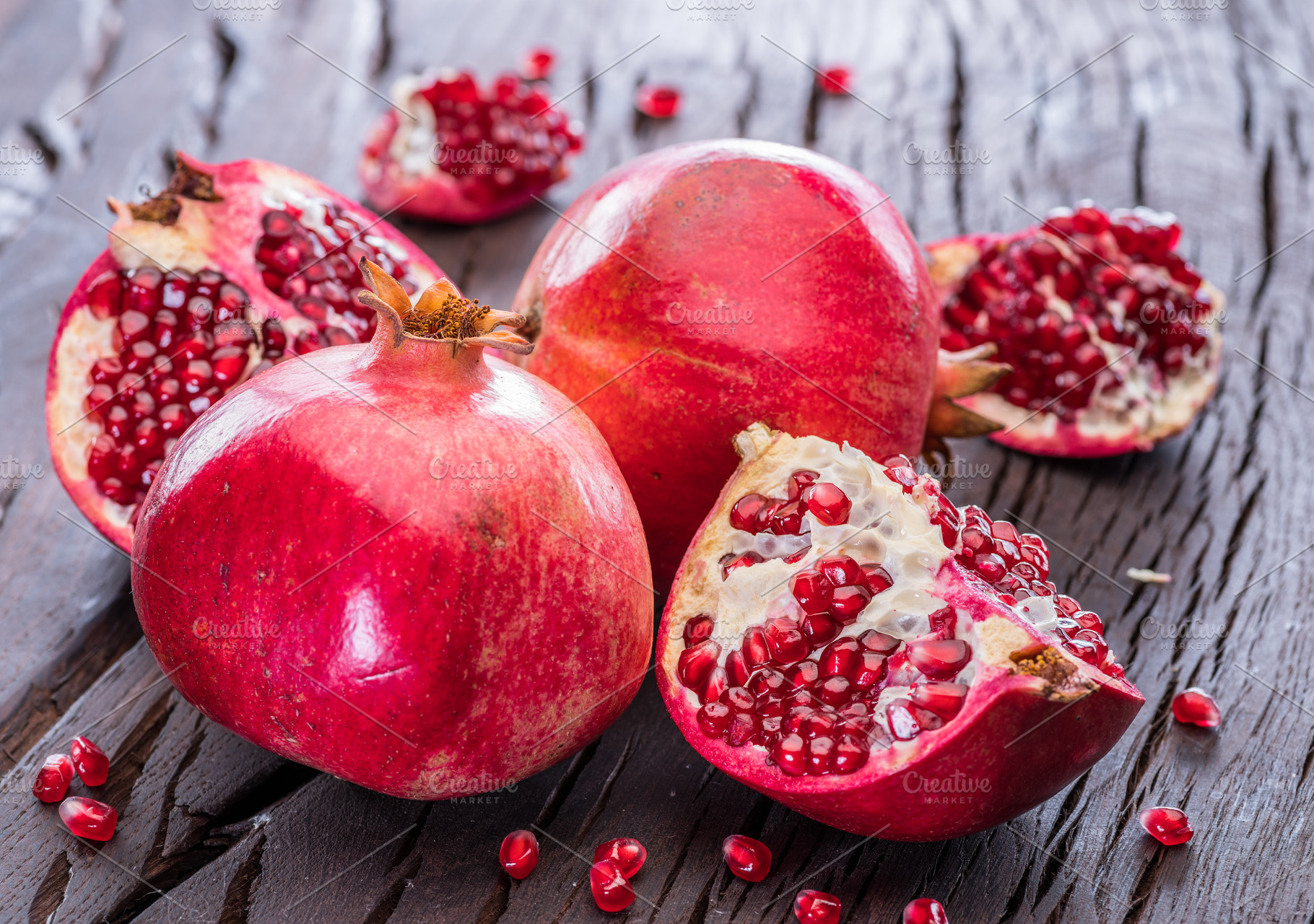 Ripe pomegranate fruits on the wooden background., a Food & Drink Photo by Volff
