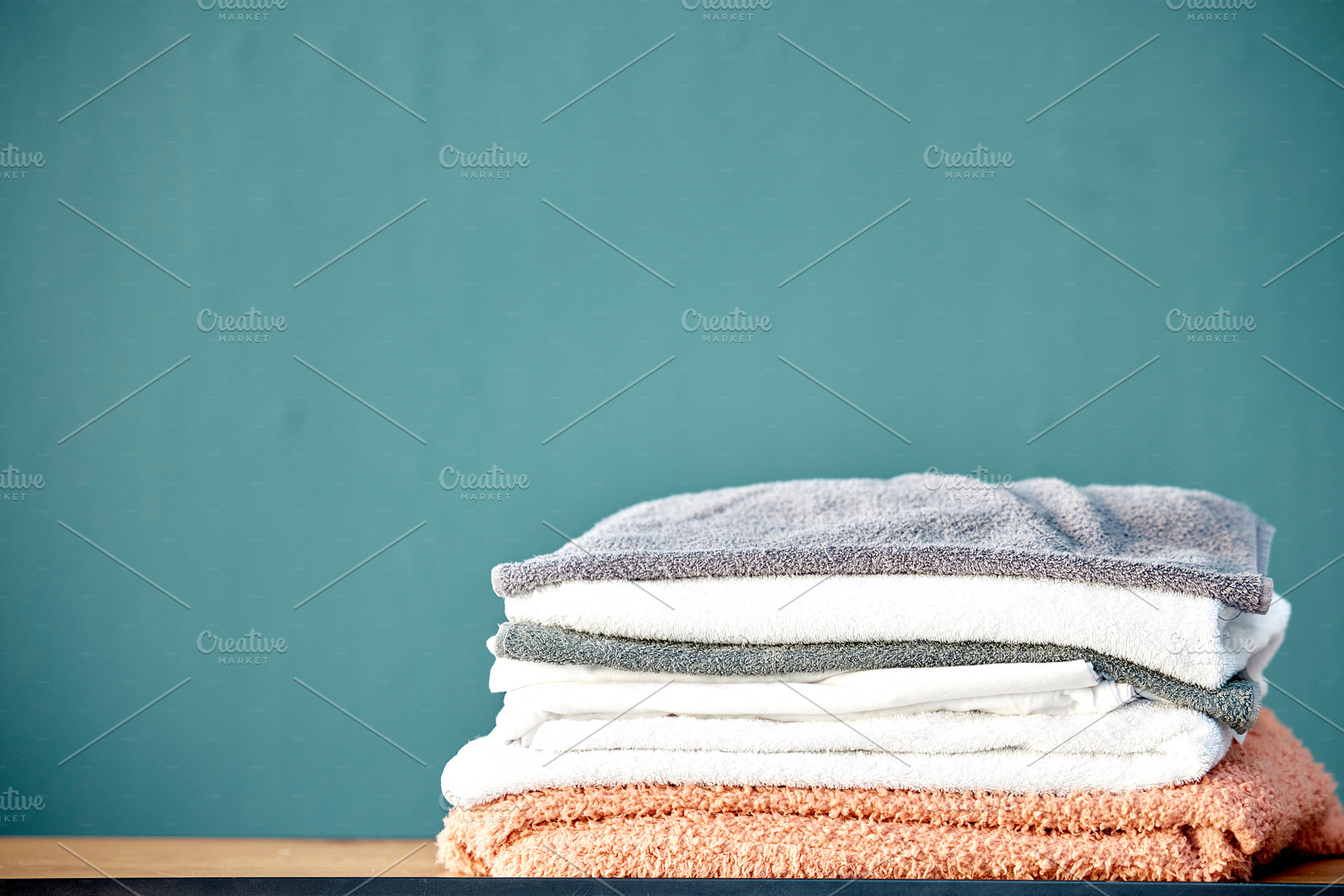 Bathroom, laundry and stack of towels on blue background for cleaning, washing and body hygiene at home. Fabric, textiles and pile of fresh, soft and clean linen for shower, bath and spa wellness, a Photo by Peopleimages.com