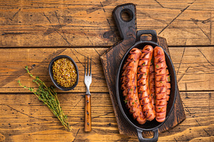 Juicy, smoky fried sausages on a wooden board with herbs and for, a Food & Drink Photo by composter-box@mail.ru