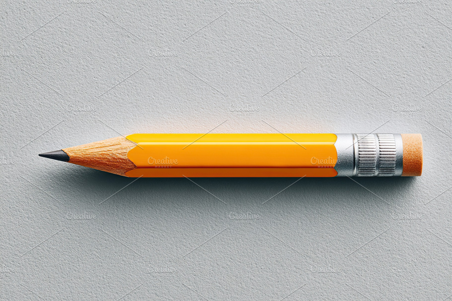 Bright yellow pencil lying flat on light gray surface adds a pop of color to wo, a Photo by AlyaAnd