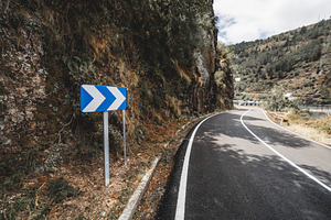 Curved mountain road with sign, a Transportation Photo by SkyNext