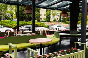 Outdoor seating area with cozy design under a transparent roof in urban setting, a Photo by AS photostudio