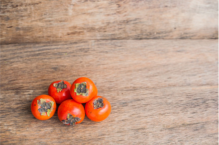 Ripe fresh persimmon on wood board, a Food & Drink Photo by Elizaveta Galitskaya