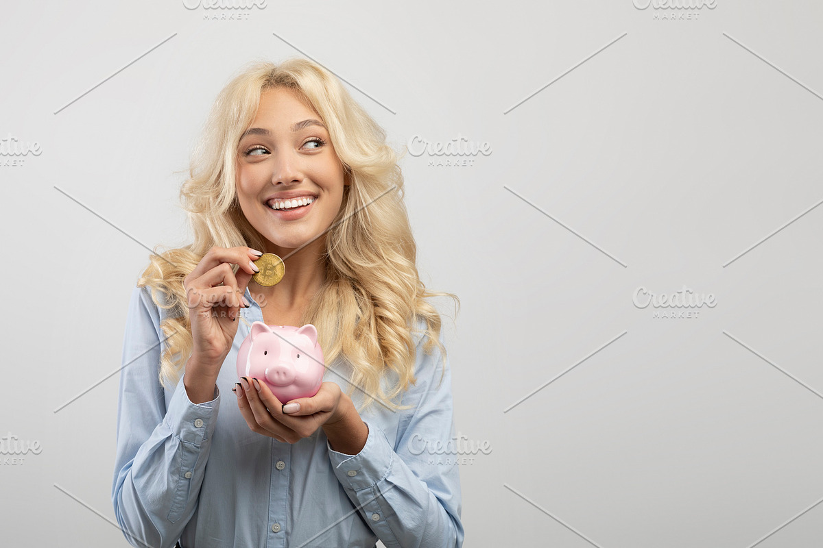 Portrait of happy woman investing in bitcoins, putting golden crypto coin into, a Photo by Prostock-Studio (Photo 1 of 2)