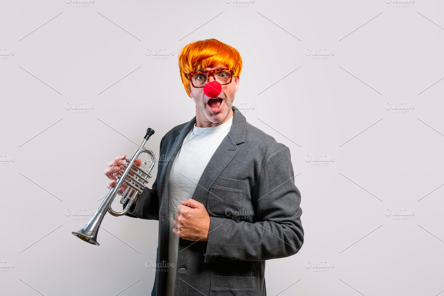 Entertainer wearing wig and clown nose playing trumpet, a Person Photo by karrastock