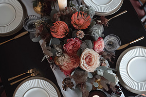 Elegant dinner table setting with floral centerpiece and candles creating a war, a Food & Drink Photo by Studio ANNA