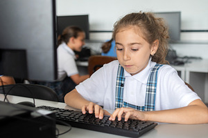 Schoolgirl Typing on Computer During Technology Class, a School & Education Photo by etorres69