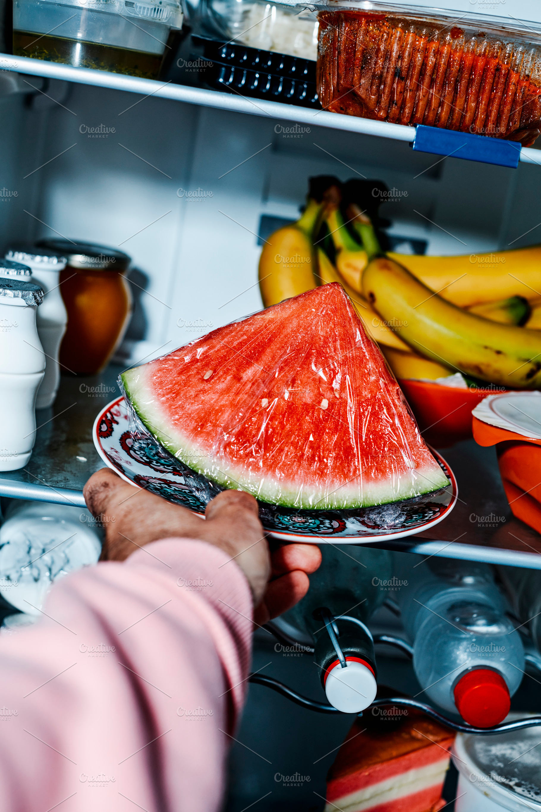a man sets a plate with watermelon in the fridge, a Photo by Nito