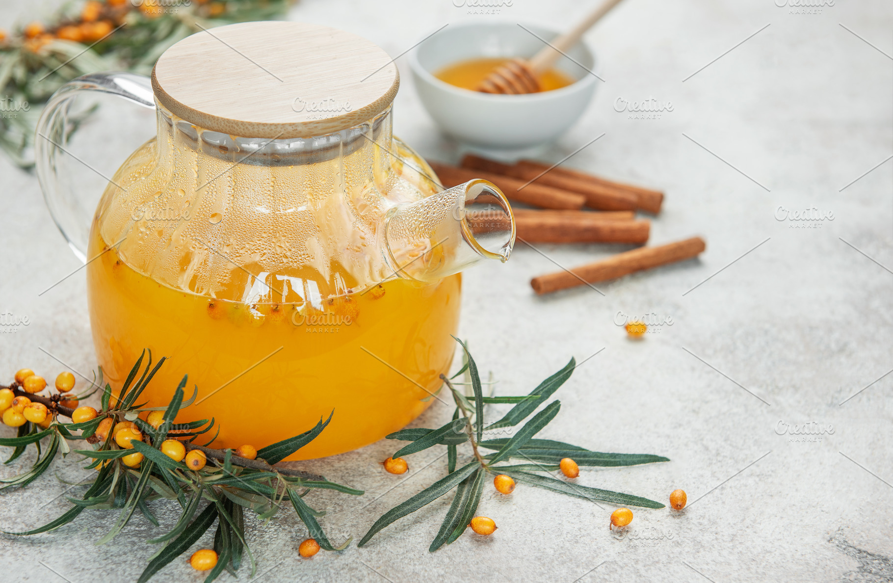 Glass teapot with sea buckthorn tea, honey and cinnamon sticks o, a Food & Drink Photo by Olena Rudo