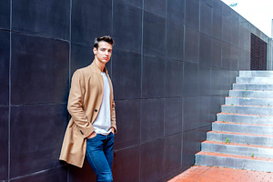 Stylish man leaning on wall with modern stairs, a Person Photo by RF Images