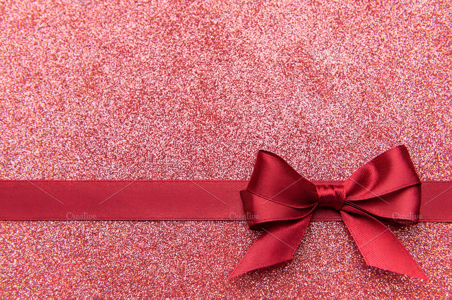 Red satin bow on glistening pink glitter background, a Holiday Photo by Olena Rudo