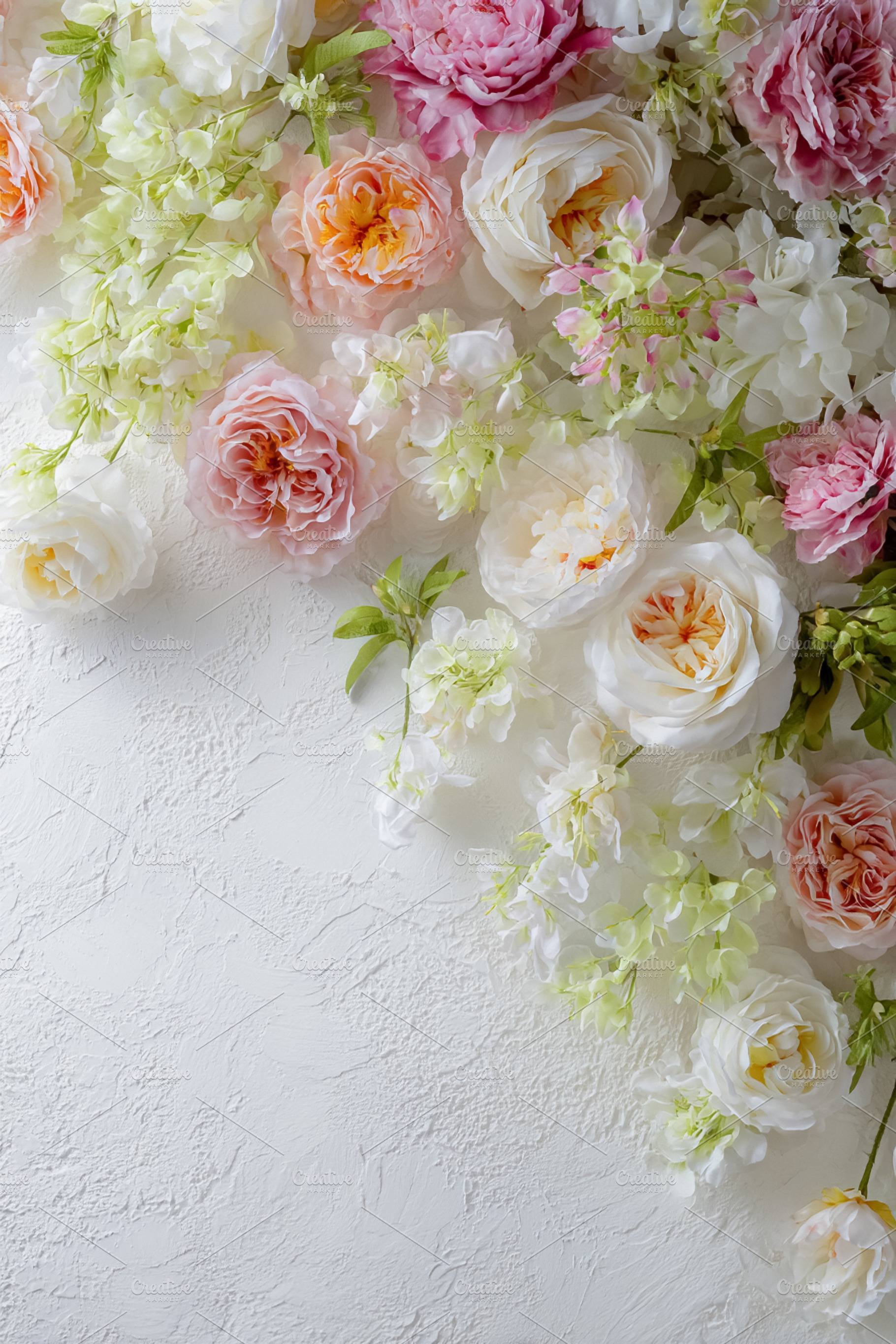 Beautiful flowers and green leaves framing a white textured back, a Photo by Studio ANNA
