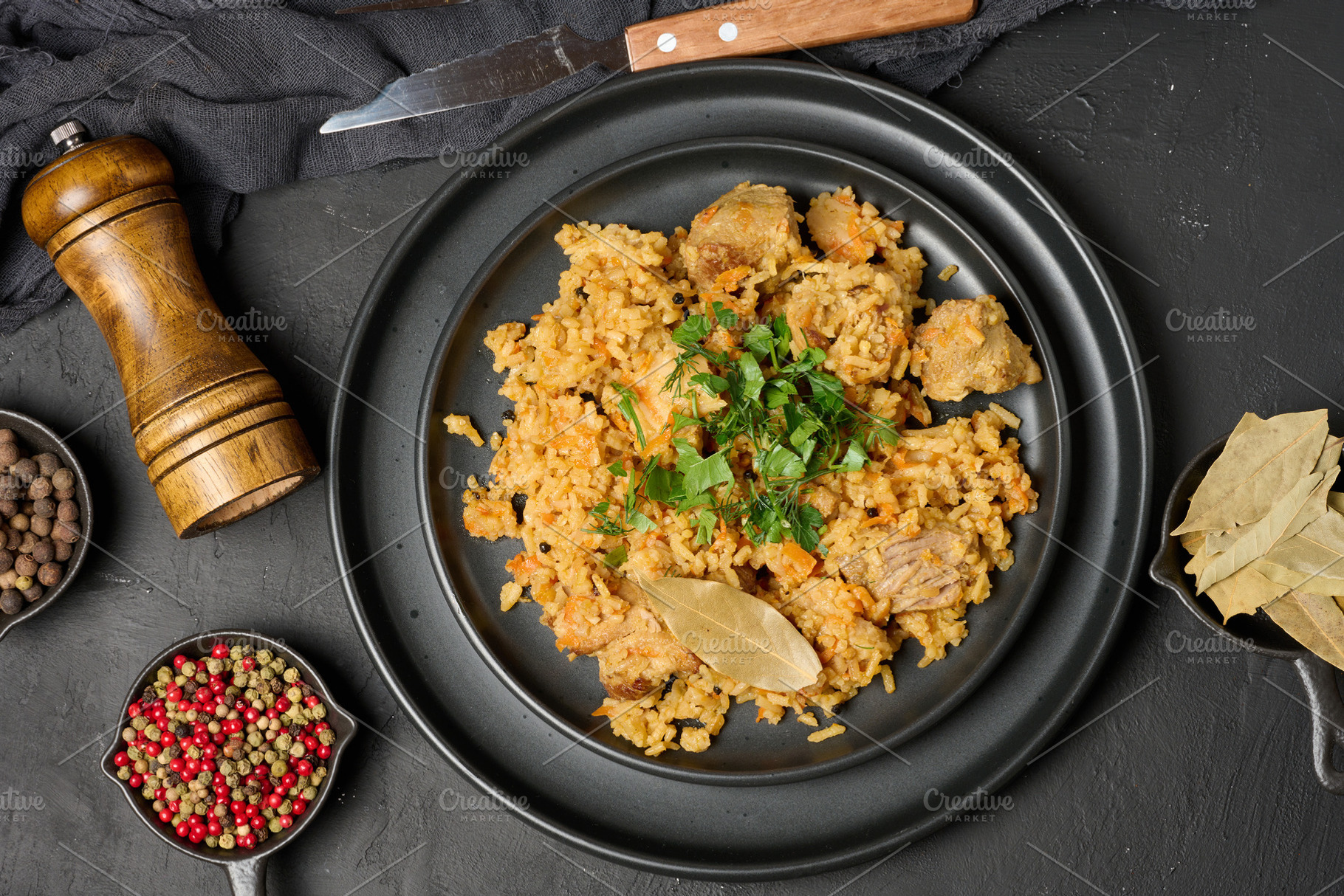 Pilaf with rice and pieces of meat in a black round plate on the, a Food & Drink Photo by ndanko