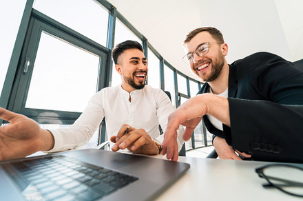 Two businessmen laugh while working, a Photo by borodai94