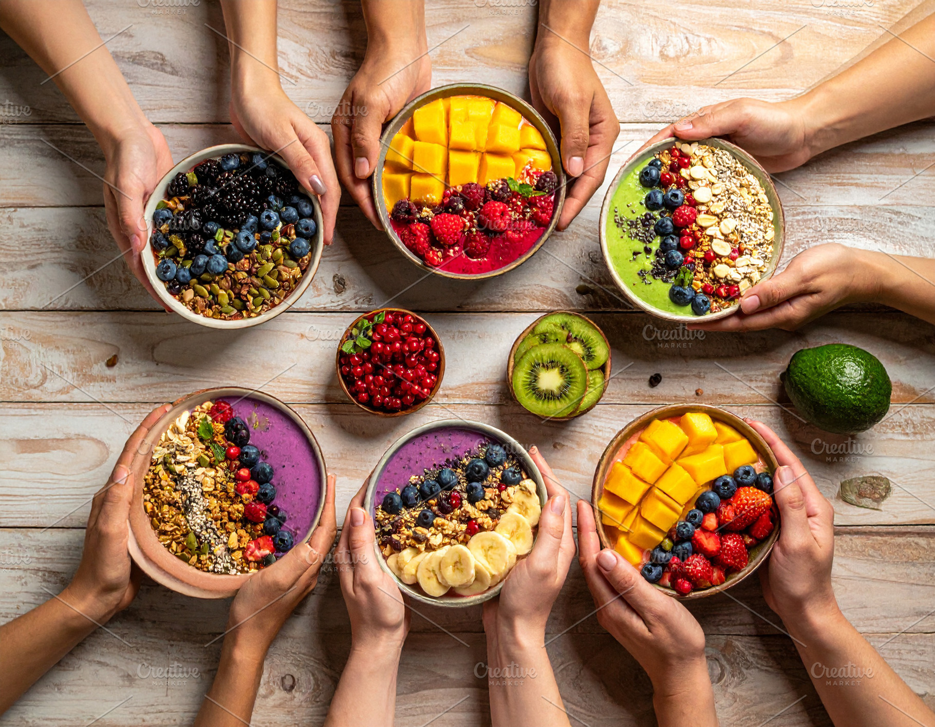 People holding smoothie bowls with fruits, seeds, and granola ov, a Food & Drink Photo by DanFLCreativo