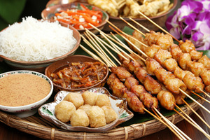 Satay skewers and shrimp with rice, sauces, and orchids arranged, a Photo by Dvoevnore photos