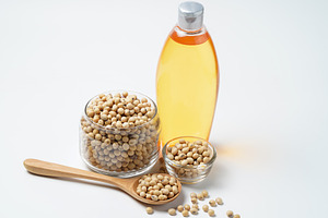 Soy beans and oil on white backgroun containing bottle, glass, and fresh