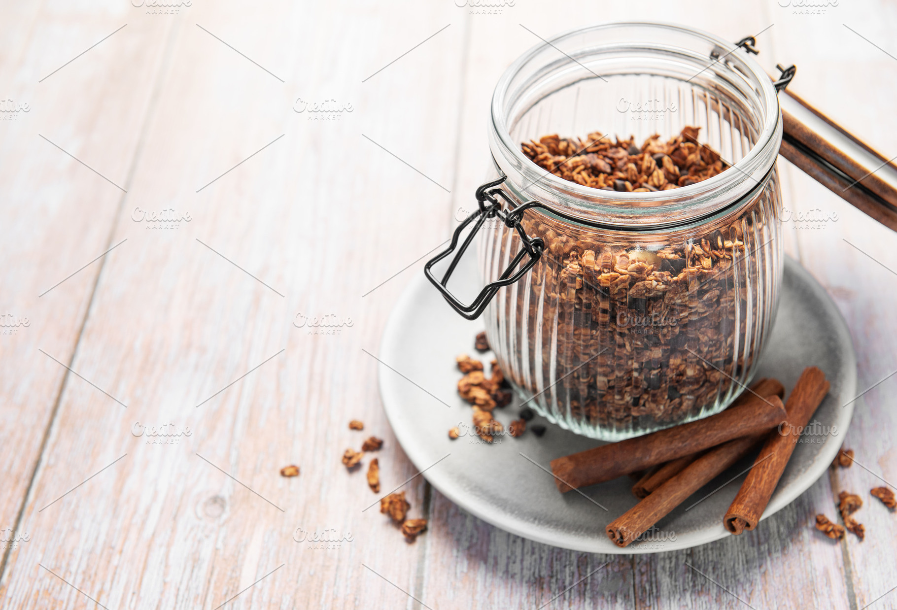 Granola cereal in glass jar with cinnamon sticks, a Food & Drink Photo by Olena Rudo