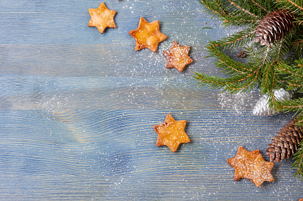 Star shaped ginger cookies and spruce branches with cones on blue wooden background text space., a Holiday Photo by Roberts & Irina Resnais