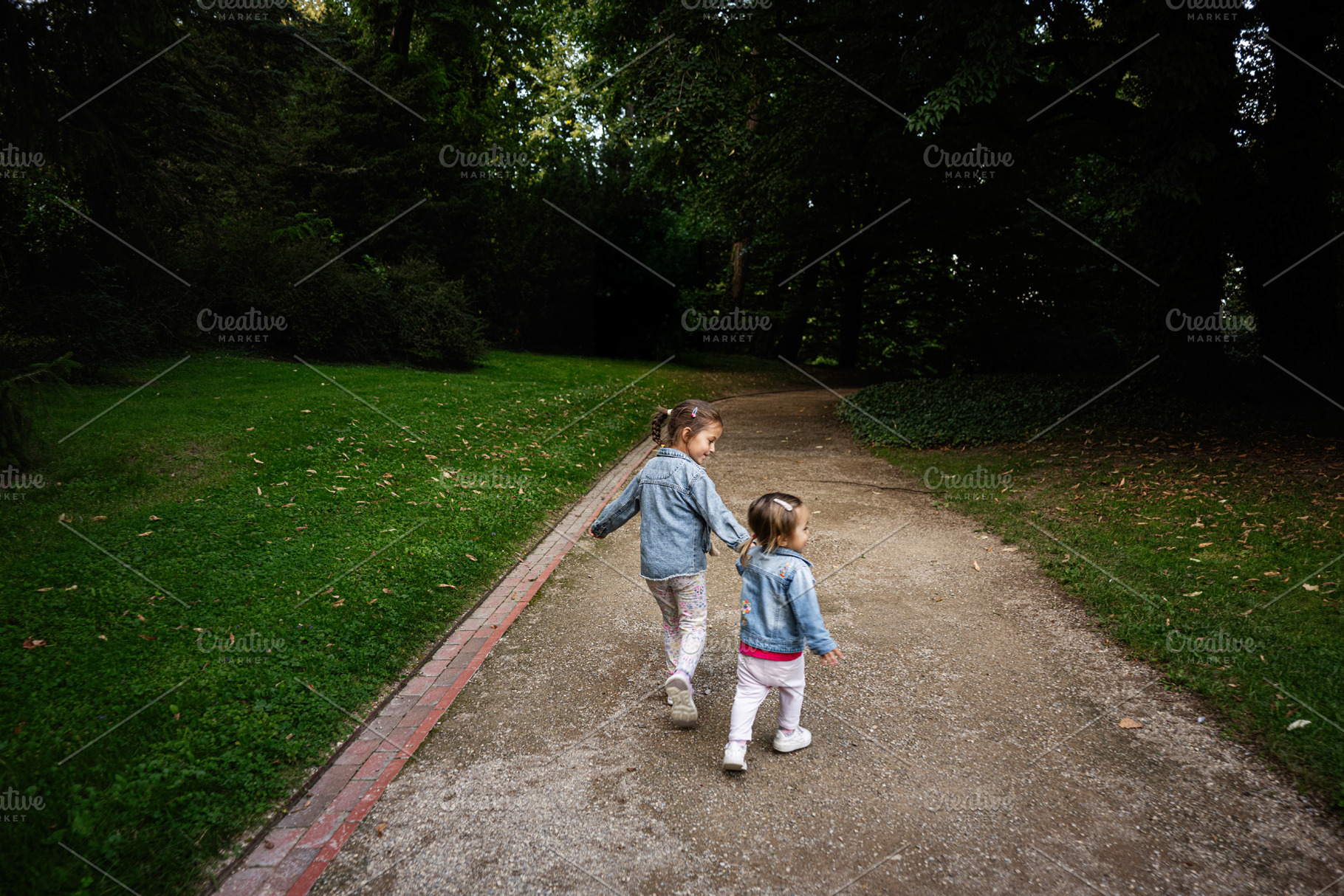 Two children walking in a park in Lancut, Poland on a sunny day, a Photo by AS photostudio