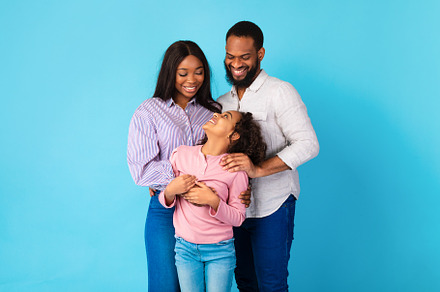 African American man hugging his wife and smiling daughter, a Background Photo by Prostock-Studio