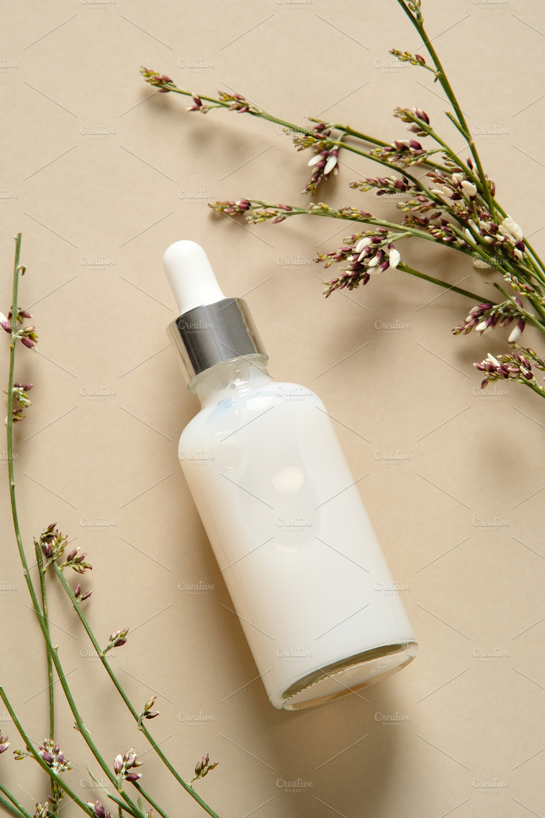 Face serum bottle with flowers on beige background. Natural cosmetics., a Health & Medical Photo by photoguns
