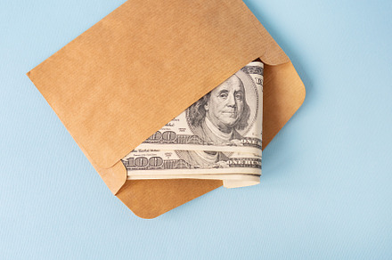 Stash of money in dollar bills coming out of an envelope on a blue background., a Business Photo by Artsaba Family