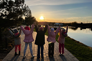 Children enjoying a sunset together by a peaceful riverside promenade, a Photo by AS photostudio