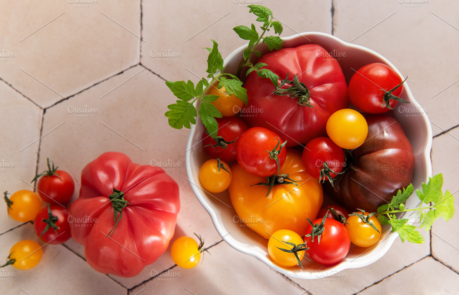 Fresh heirloom tomatoes in bowl on tile surface, a Food & Drink Photo by Olena Rudo