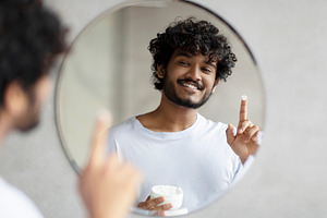 Skincare for men. Handsome indian man applying moisturising cream on face, look, a Person Photo by Prostock-Studio