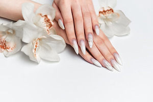 Elegant hands displaying long white almond nails with orchid flo, a Health & Medical Photo by Olena Rudo