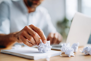 Man brainstorming at desk with crumpled paper, a Business Photo by AlyaAnd