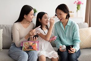 Makeup spa day concept. Adorable little girl Asian with mother and granny apply, a Photo by Prostock-Studio