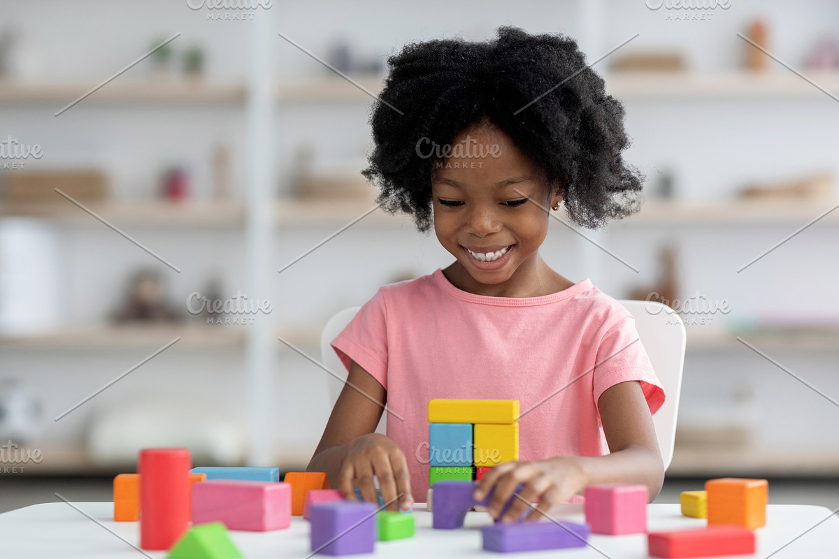 Smiling little african american girl playing with colorful wooden blocks, a Photo by Prostock-Studio (Photo 2 of 2)