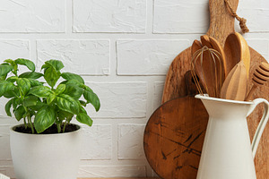 Kitchen utensils and basil plant creating a rustic culinary scen, a Photo by Olena Rudo