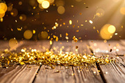 Golden sparkles falling gently on wooden table in sunlight, a Holiday Photo by GoodGoods (Thumbnail 1 of 2)
