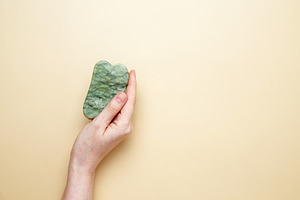 Female hand holding marble gua sha tools for skincare routine, a Photo by matucha