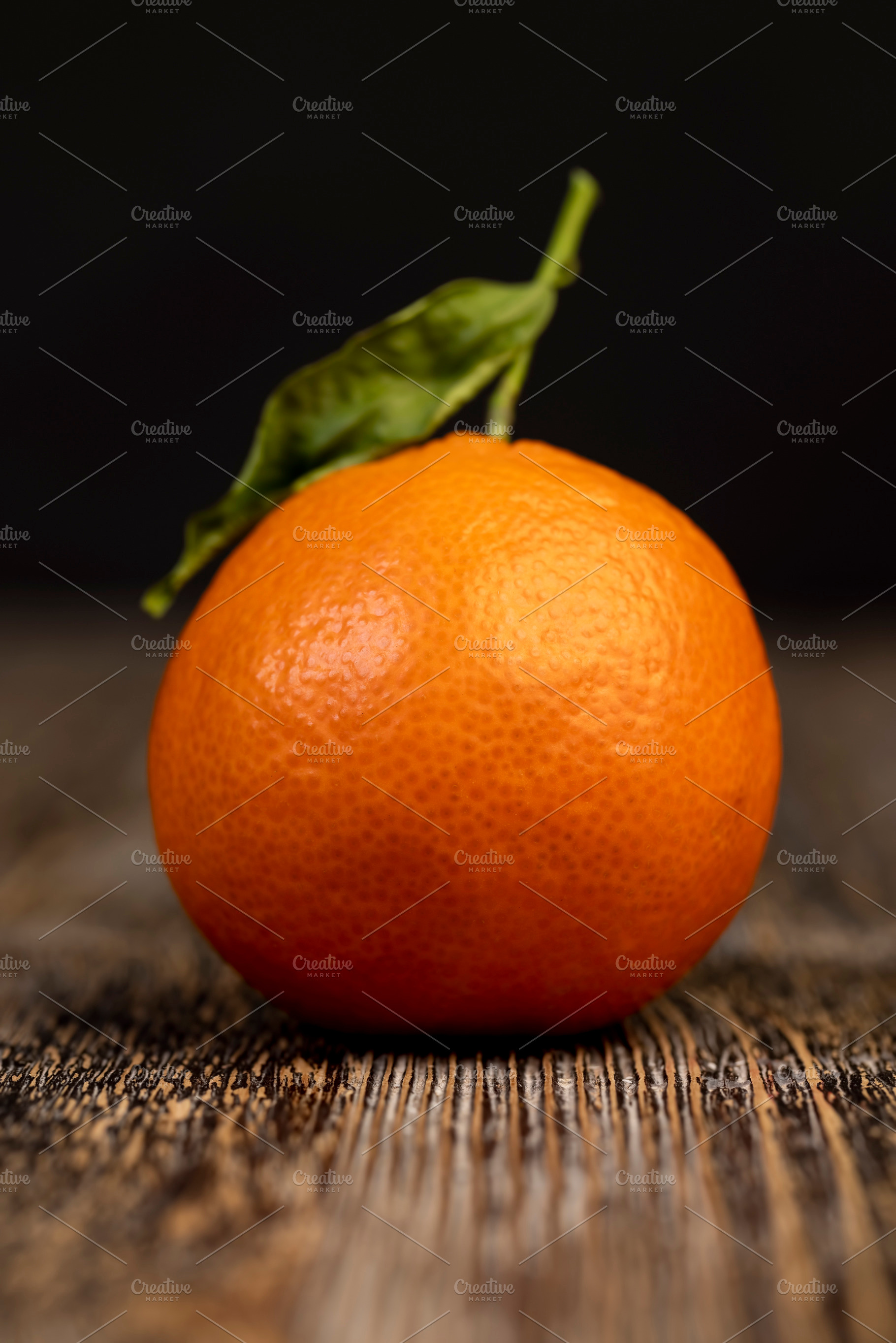 one ripe tangerine with a dried green leaf, a Photo by rsoollAI