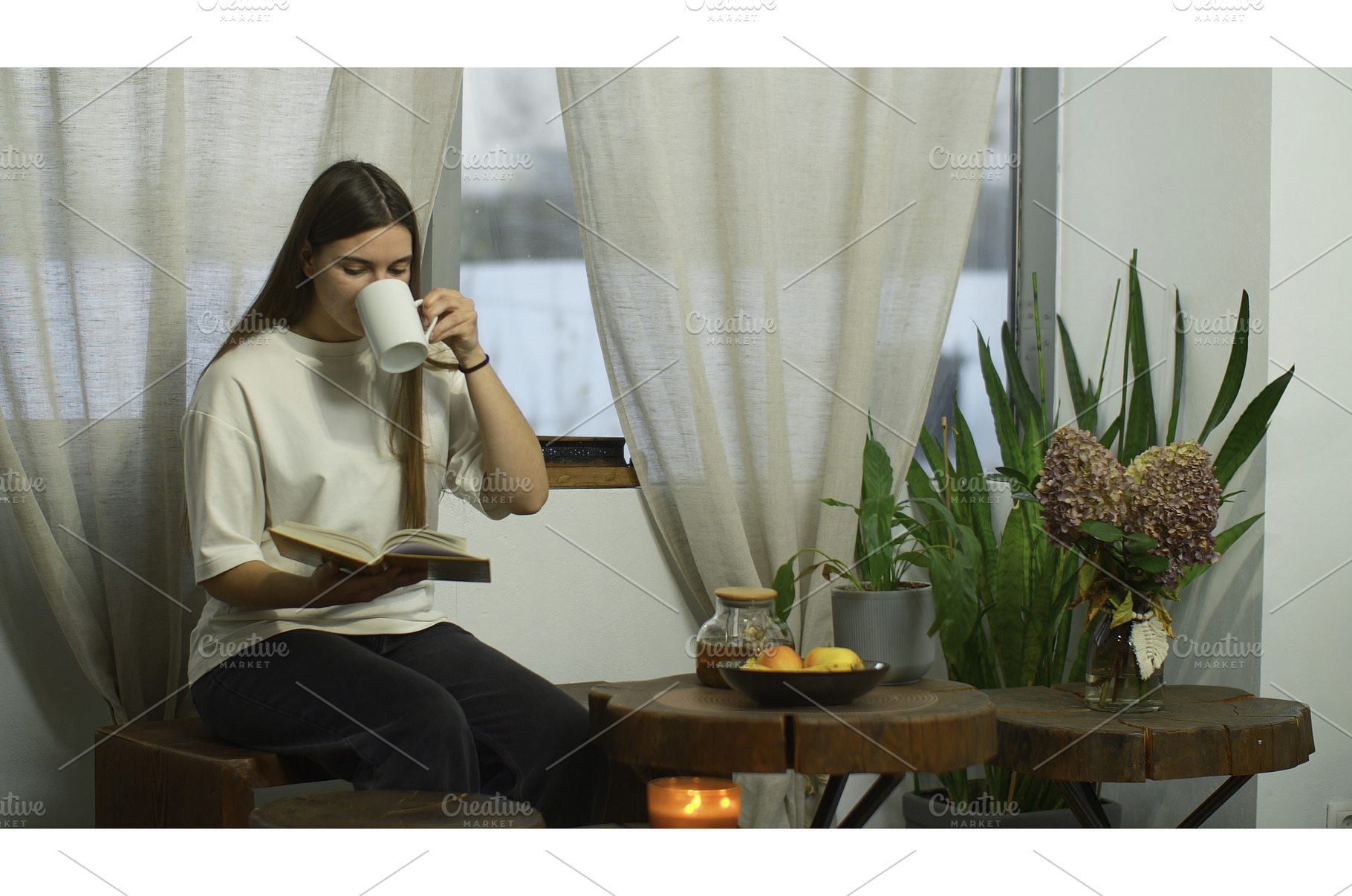 Young woman is reading book with tea, a Person Photo by Media Whale Stock