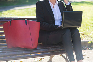 Businesswoman calling with laptop in sunny park, a Photo by RF Images
