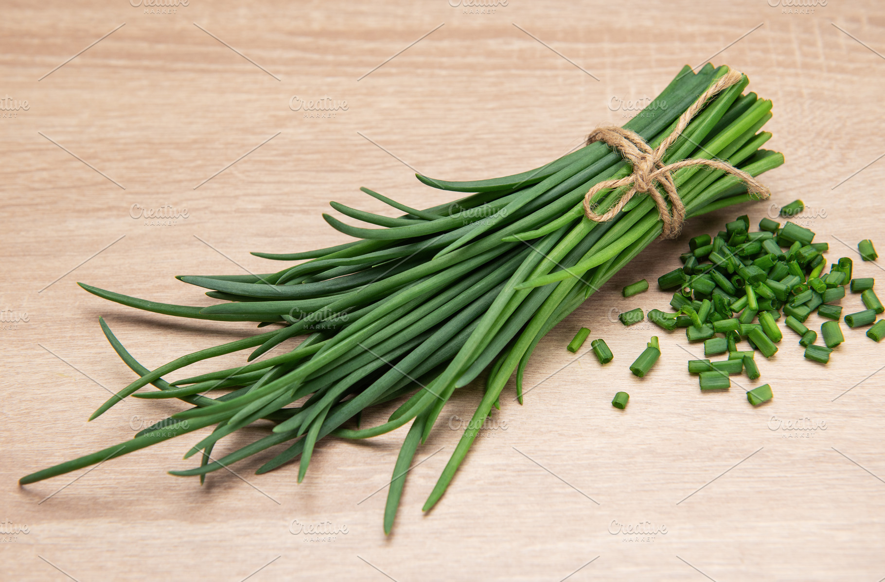 Fresh chives tied with twine on wooden table with chopped chives, a Food & Drink Photo by Olena Rudo