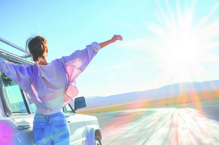 A woman stands with her arms outstretched in front of a vehicle, enjoying a sun, an Arts & Entertainment Photo by Textures & Backgrounds