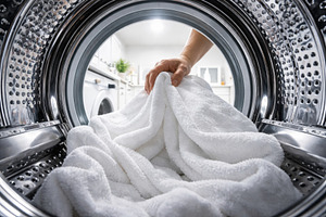 Laundry being placed in a washing ma, a Photo by Dvoevnore photos
