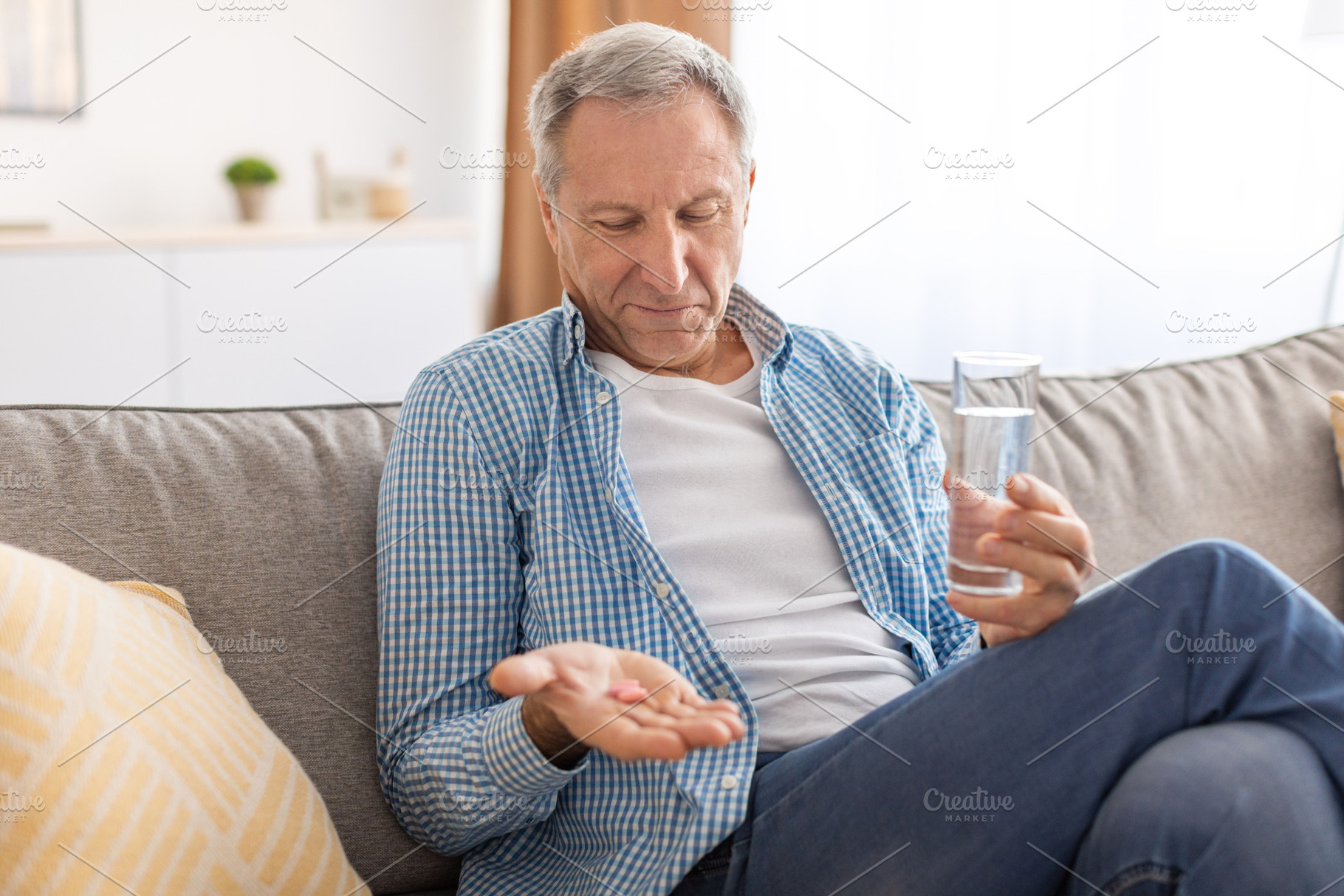 Mature man taking pills holding glass of water, a Photo by Prostock-Studio